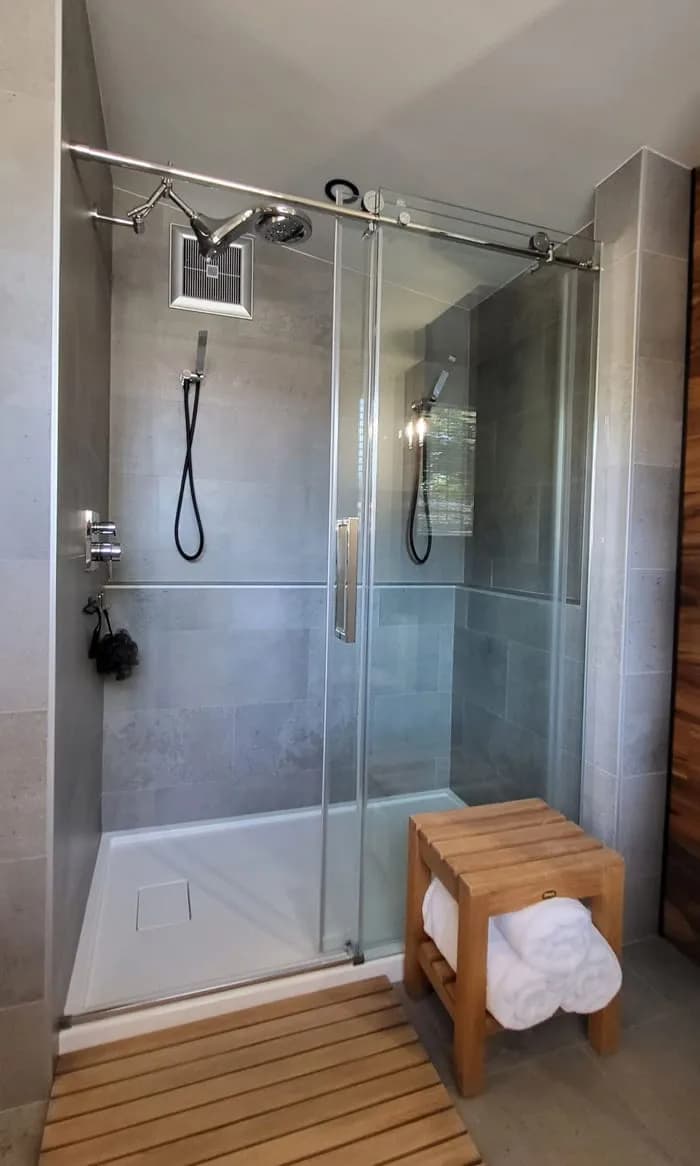 Vitre de douche coulissante, avec banc en bois et caillebotis