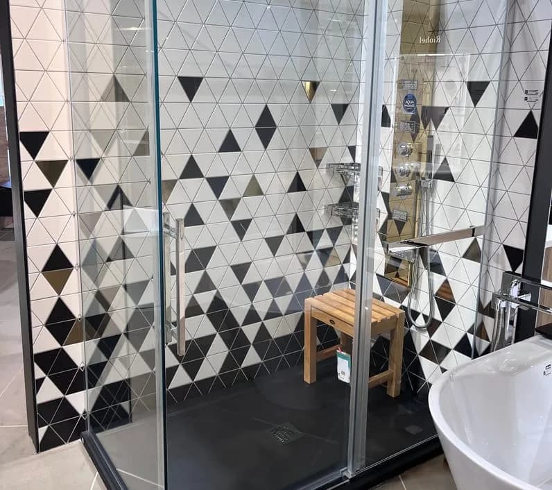 Douche vitrée à cadre noir devant une céramique à motifs de triangles