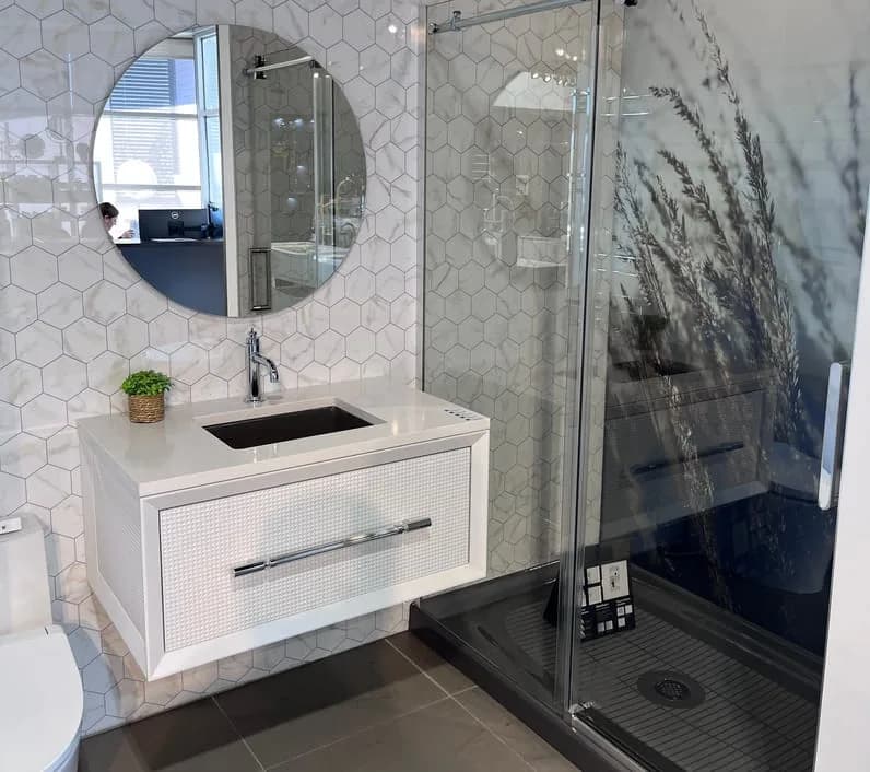 Vitre de douche coulissante près d’un meuble-lavabo blanc et d’un miroir rond