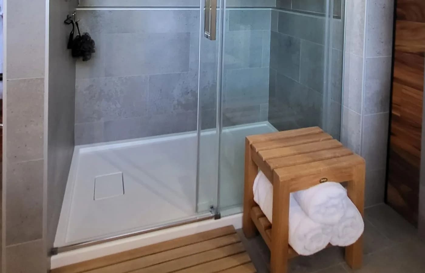 Vitre de douche coulissante avec banc en bois et serviettes roulées